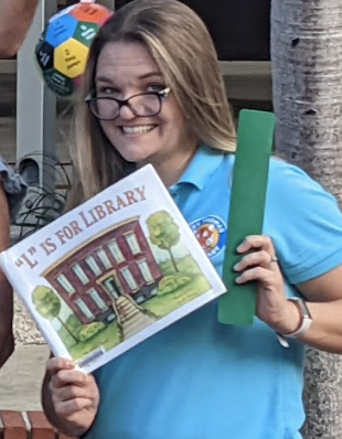Mrs. Wilson holding a library book and shelf marker